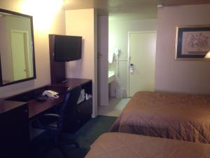 a hotel room with a desk and a bed and a mirror at Colonial Inn Monahans TX in Monahans