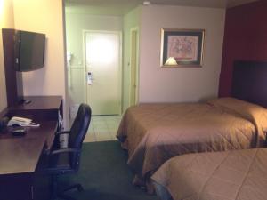 a hotel room with two beds and a desk and a chair at Colonial Inn Monahans TX in Monahans