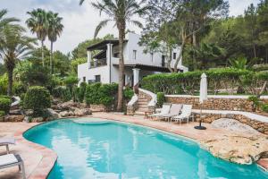 una piscina frente a una casa con palmeras en Can Blay en Santa Eulalia del Río