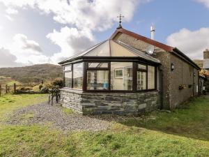 a small cottage with a large glass window at Melin Newydd in Llanfihangel-y-pennant
