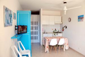 サン・ヴィート・ロ・カーポにあるFranco e Mimmaのキッチン(テーブル、白い椅子、青いドア付)