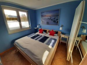 a blue bedroom with a large bed with red pillows at Ferienwohnungen ÜckeRitz mit PKW Stellplatz bei Familie Habben-Hollander in Ueckeritz