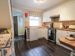 a kitchen with white cabinets and a wooden floor at Scarborough Cottage in Great Driffield