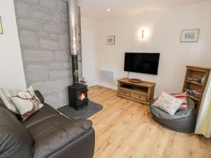 a living room with a couch and a wood stove at Melin Newydd in Llanfihangel-y-pennant