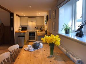 une cuisine avec une table en bois et des fleurs jaunes. dans l'établissement Little Coombe, Bookham Court, à Dorchester