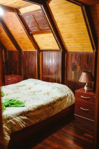 a bedroom with a bed and a table with a lamp at Chalé do Vale Encantado in Campos do Jordão