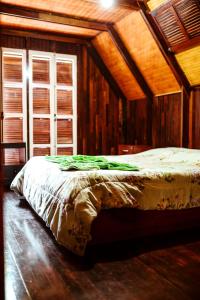 a bed in a room with wooden walls at Chalé do Vale Encantado in Campos do Jordão