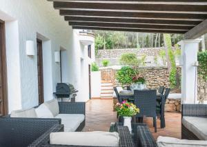 un patio con sillas, mesas y una pared de piedra. en Can Blay, en Santa Eulària des Riu