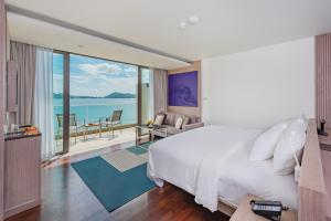 a bedroom with a large bed and a balcony at Oceanfront Beach Resort - SHA Extra Plus in Patong Beach