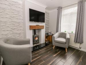 a living room with two chairs and a fireplace at Scarborough Cottage in Great Driffield