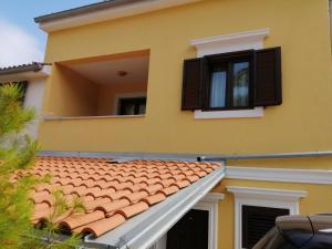 a yellow house with a red roof and windows at Christian in Mali Lošinj