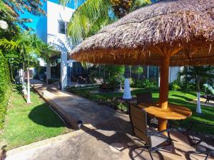 梅里達的住宿－Casa Xcanatun，稻草伞下的桌子和椅子