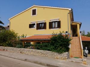 a yellow house with a stone wall at Christian in Mali Lošinj