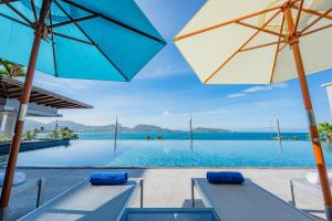 a pool with two benches and an umbrella at Oceanfront Beach Resort - SHA Extra Plus in Patong Beach
