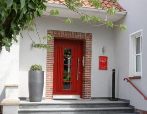 una puerta roja de una casa blanca con una puerta roja en Tiemanns Boardinghouse, en Lemförde