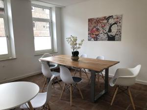 ein Esszimmer mit einem Holztisch und weißen Stühlen in der Unterkunft RÜ Business Apartments & Suites in Essen