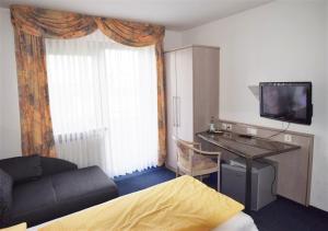 a room with a bed and a desk and a window at Hotel Alena - Kontaktlos Check-In in Filderstadt