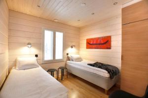 a bedroom with two beds in a room with wooden walls at Lapland Dream Villas in Rauhala