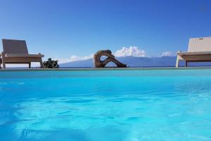 a pool with two chairs and a sculpture in the water at Villa Ora in Teavaro