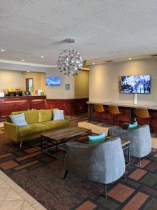 a lobby with a couch and chairs and a tv at Foxwood Inn & Suites Drayton Valley in Drayton Valley