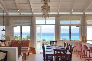 a dining room with a table and chairs and the ocean at Villa Ora in Teavaro