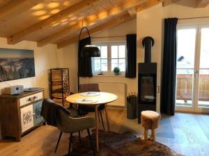 a living room with a table and chairs and windows at Bodenschneid Suiten Neureuthblick in Kreuth