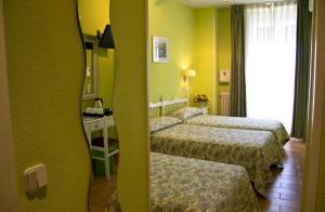 una camera d'albergo con tre letti e uno specchio di Hostal Los Alpes a Madrid
