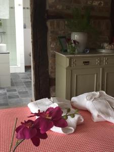 uma mesa com toalhas brancas e flores roxas em PuurTeuven B&B tussen Kunst en Natuur em Voeren