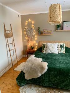 1 dormitorio con 1 cama con manta verde y escalera en Super cosy cottage in heart of Dalarna, en Västra Fors
