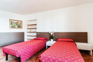 two beds in a room with red sheets at Il Roseto di Marina in Lucino