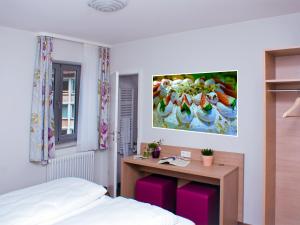 1 dormitorio con cama, escritorio y una pintura en la pared en Gästehaus Eschers Eiswerk, en Annweiler am Trifels