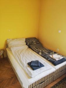 a bed in a room with a yellow wall at Belvárosi minilakás 2 főre in Pécs