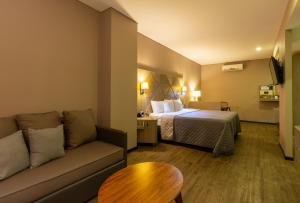 Habitación de hotel con cama y sofá en Hotel Glow Point - Mulza en León