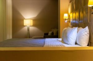 Habitación de hotel con cama con almohadas blancas en Hotel Glow Point - Mulza, en León