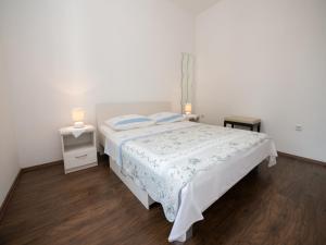 a white bedroom with a bed and two lamps at Apartment Marina with Sea View in Lovran