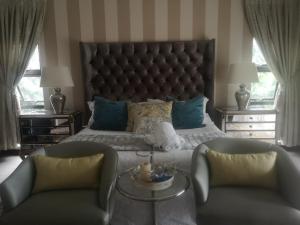 a bedroom with a large bed and two chairs at Bristow Luxury Suites With Back Up Power and Free Wi-Fi in Roodepoort