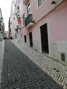 uma rua de paralelepípedos numa cidade com edifícios cor-de-rosa em Residencial Camoes em Lisboa