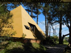 une maison jaune assise au-dessus d'un champ dans l'établissement Piramide, à Punta del Diablo