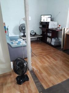 a room with a floor fan and a room with a tv at Hostel Rota do Vale in Blumenau
