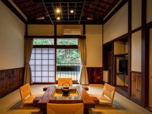 uma sala de estar com uma mesa e cadeiras e uma grande janela em Shirakabeso em Izu
