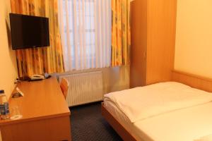 a hotel room with a bed and a desk with a television at City Hotel Neuwied in Neuwied