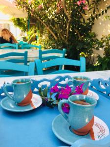 ボズジャ島にあるPosthane Hotelの青いテーブルと花の上のコーヒー3杯
