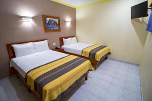 a hotel room with two beds and a tv at Hotel El Español Centro Historico in Mérida