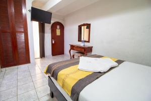 sypialnia z łóżkiem, komodą i lustrem w obiekcie Hotel El Español Centro Historico w mieście Mérida