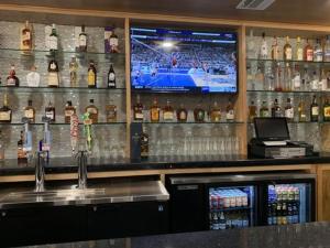 a bar with a television and a counter with alcohol at Hawthorn Suites By Wyndham Odessa in Odessa