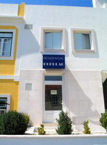 a white building with a blue sign on it at Residencial Popular in Peniche