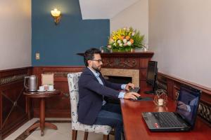 a man sitting at a table with a laptop computer at Hotel Florida in Ambato