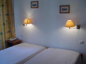 a bedroom with two beds and a phone and two lamps at Residencial Popular in Peniche