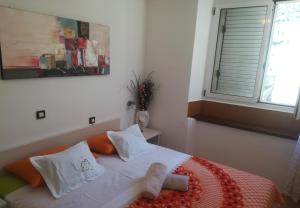 a bed with white pillows and a window in a room at Apartment JoviZ - 20m from the sea in Makarska