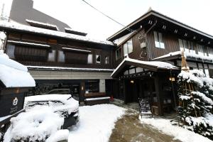 a snow covered house with a car parked in front of it at Shiro Nozawa in Nozawa Onsen